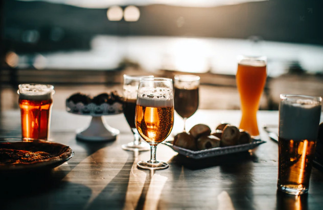 Photo of assortment of beers being enjoyed outdoors with food